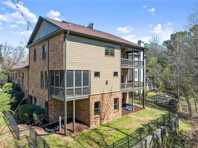 back of property with a lawn, brick siding, a balcony, and a fenced backyard