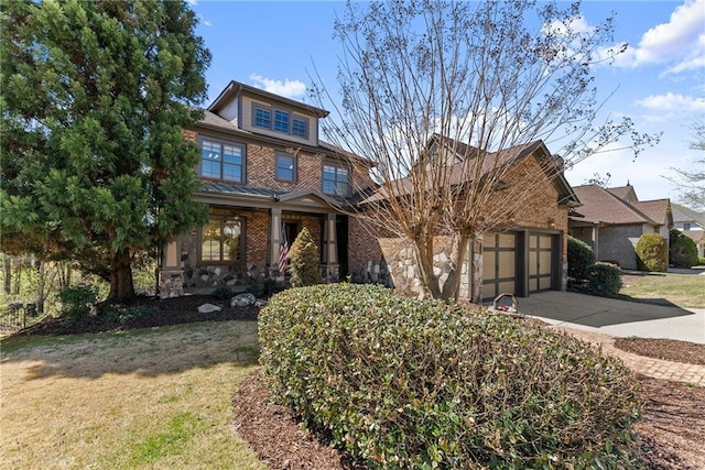 craftsman-style house with brick siding, an attached garage, a front yard, and concrete driveway