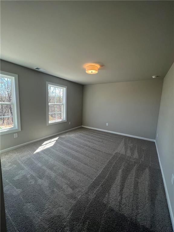 unfurnished room featuring dark colored carpet