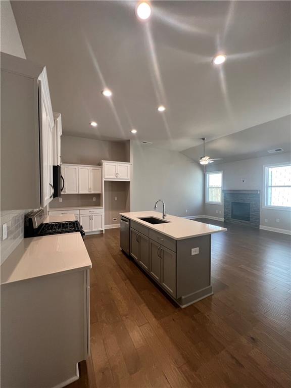 kitchen with sink, ceiling fan, gas range oven, an island with sink, and plenty of natural light