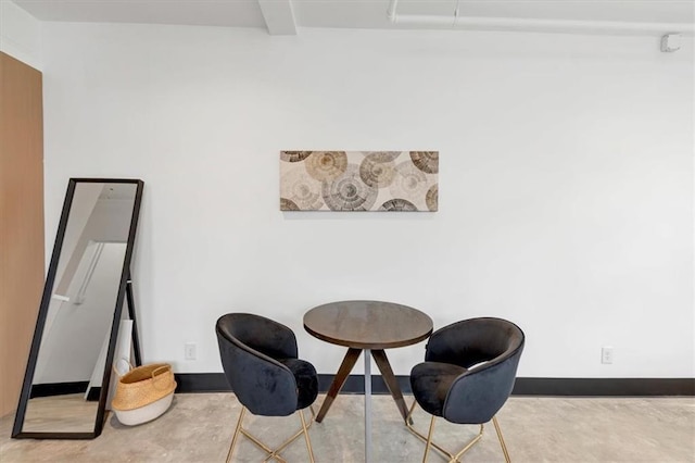 living area with beamed ceiling and concrete floors