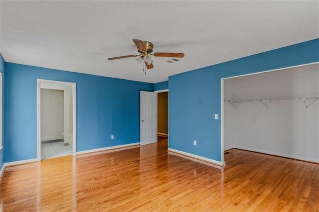 unfurnished bedroom featuring hardwood / wood-style flooring, a textured ceiling, ceiling fan, and a closet