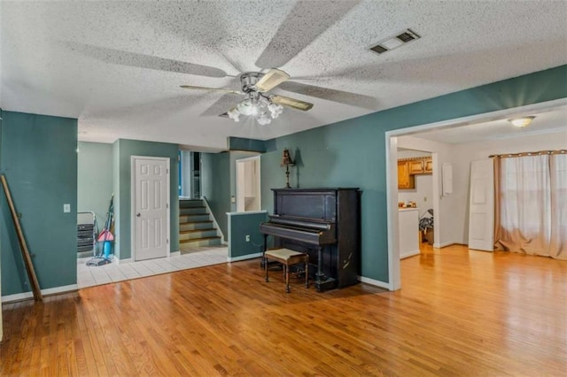 miscellaneous room featuring a textured ceiling, light wood-type flooring, and ceiling fan