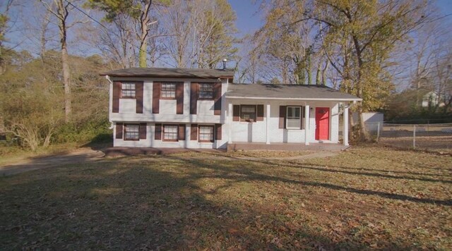 split level home featuring a front lawn and fence