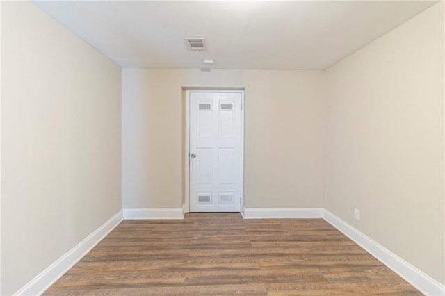 spare room featuring baseboards, visible vents, and wood finished floors