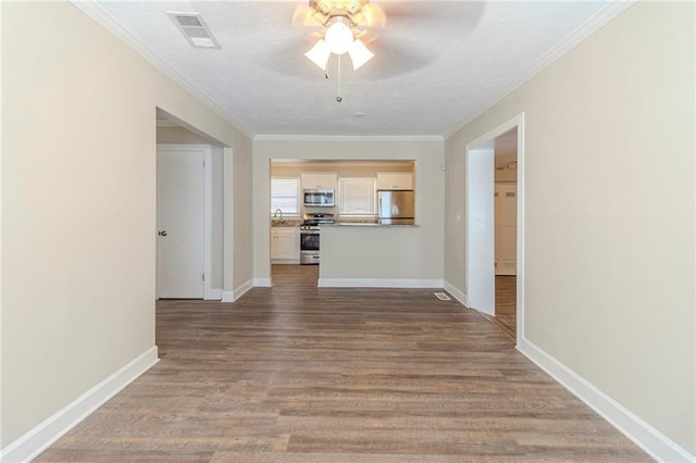 interior space with visible vents, crown molding, baseboards, and wood finished floors