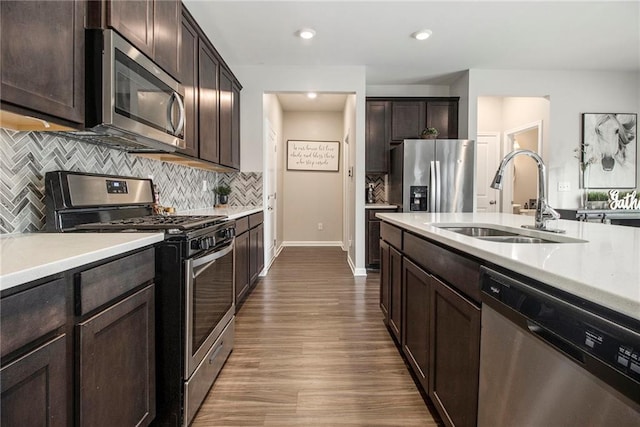 kitchen featuring sink, tasteful backsplash, wood-type flooring, dark brown cabinets, and stainless steel appliances