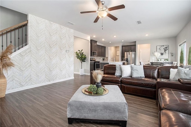 living room featuring ceiling fan, sink, and dark hardwood / wood-style floors