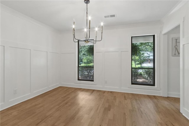 9165 Eves Cir, Roswell, GA 30076 - unfurnished dining area with a decorative wall, a chandelier, light wood finished floors, crown molding, and a wainscoted wall