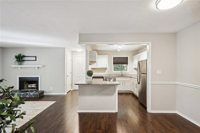 kitchen with appliances with stainless steel finishes, sink, white cabinets, light stone countertops, and dark wood-type flooring