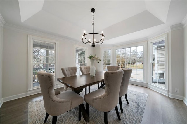 dining area featuring a chandelier, dark wood-type flooring, and a raised ceiling