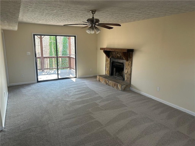 unfurnished living room with a stone fireplace, a textured ceiling, ceiling fan, and carpet