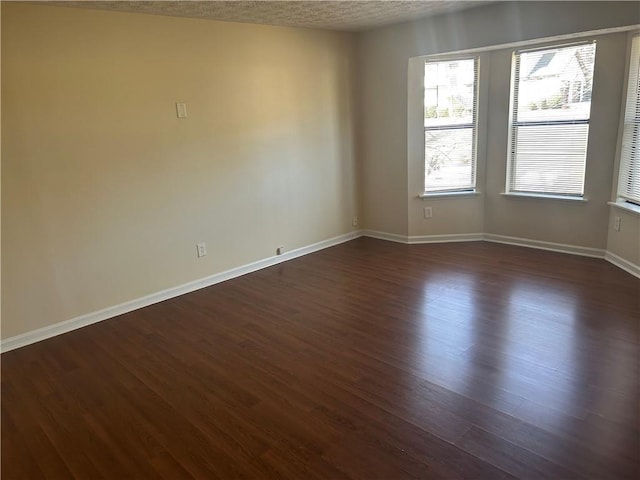 unfurnished room featuring dark wood-type flooring and a textured ceiling