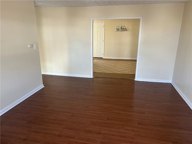 unfurnished room with dark hardwood / wood-style flooring and a chandelier