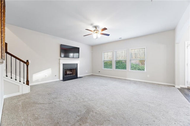 unfurnished living room with ceiling fan and dark colored carpet