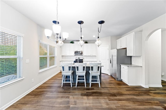 kitchen featuring stainless steel appliances, white cabinetry, hanging light fixtures, and dark hardwood / wood-style floors