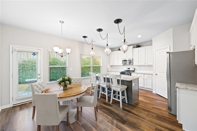 dining room featuring a healthy amount of sunlight, dark wood-type flooring, and a chandelier