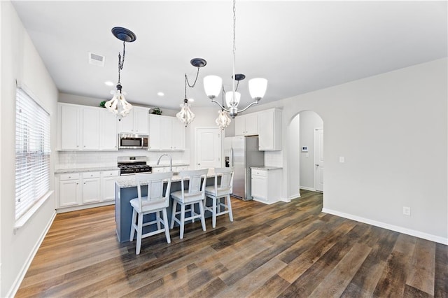 kitchen featuring dark hardwood / wood-style floors, white cabinetry, stainless steel appliances, and hanging light fixtures