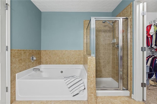 80 Riley Place Dr, Dawsonville, GA 30534 - bathroom featuring a bath, a shower stall, a walk in closet, a textured ceiling, and tile patterned flooring