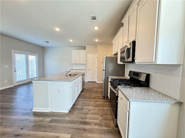 kitchen featuring an island with sink, stainless steel appliances, light stone countertops, light wood-type flooring, and white cabinets