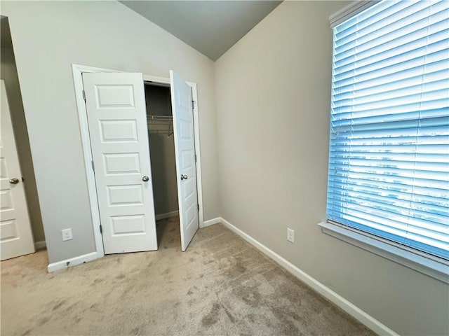 unfurnished bedroom with light carpet, a closet, and vaulted ceiling