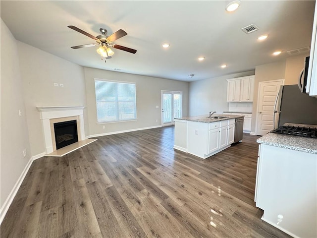 kitchen with appliances with stainless steel finishes, an island with sink, white cabinetry, and dark hardwood / wood-style flooring