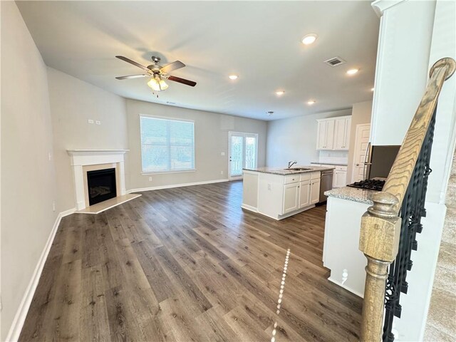 kitchen featuring dark wood-type flooring, stainless steel appliances, a center island with sink, sink, and white cabinetry