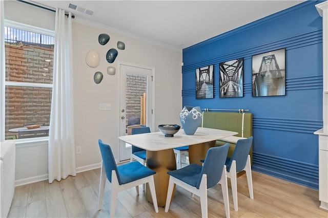 dining space featuring baseboards, visible vents, crown molding, and wood finished floors