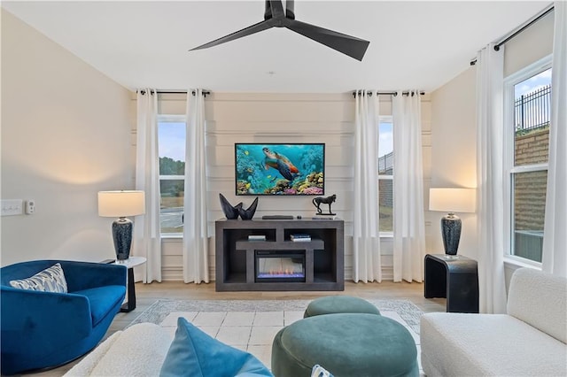 living room with ceiling fan, a glass covered fireplace, and a healthy amount of sunlight