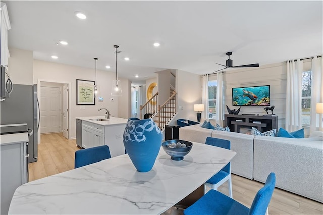 dining room with stairway, light wood-type flooring, a ceiling fan, and recessed lighting