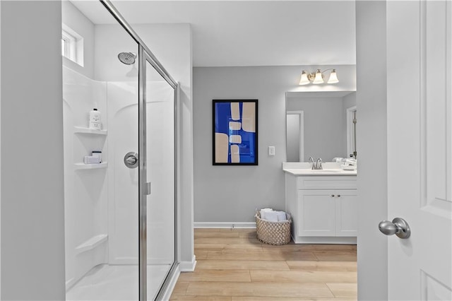 bathroom with a stall shower, wood finished floors, vanity, and baseboards