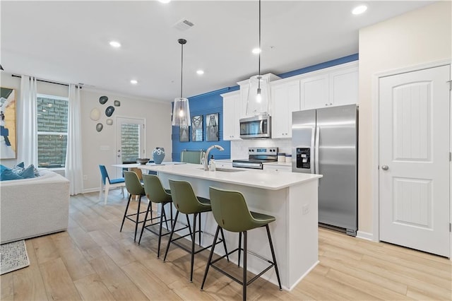 kitchen featuring a breakfast bar, stainless steel appliances, tasteful backsplash, visible vents, and a kitchen island with sink