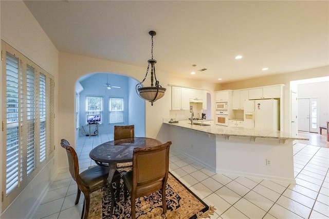 tiled dining space featuring ceiling fan and sink