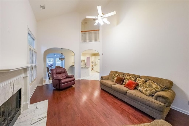 living room featuring a fireplace, hardwood / wood-style floors, high vaulted ceiling, and ceiling fan