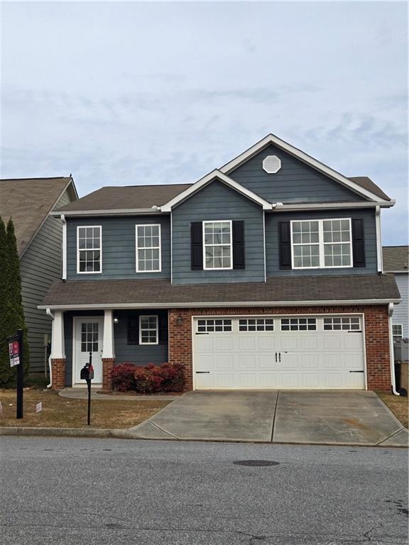 traditional-style home featuring a garage, brick siding, and driveway