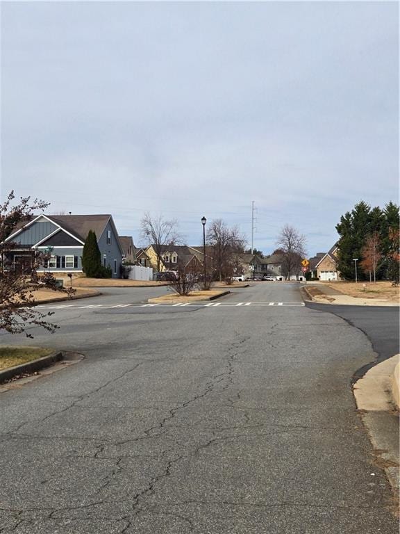 view of street featuring street lights, curbs, sidewalks, and a residential view