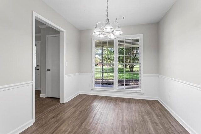 unfurnished dining area featuring dark wood-type flooring and a notable chandelier