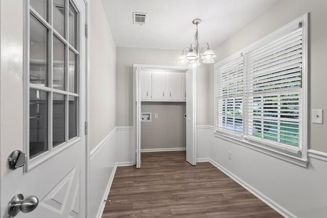 interior space with cabinets, a notable chandelier, dark hardwood / wood-style flooring, and washer hookup