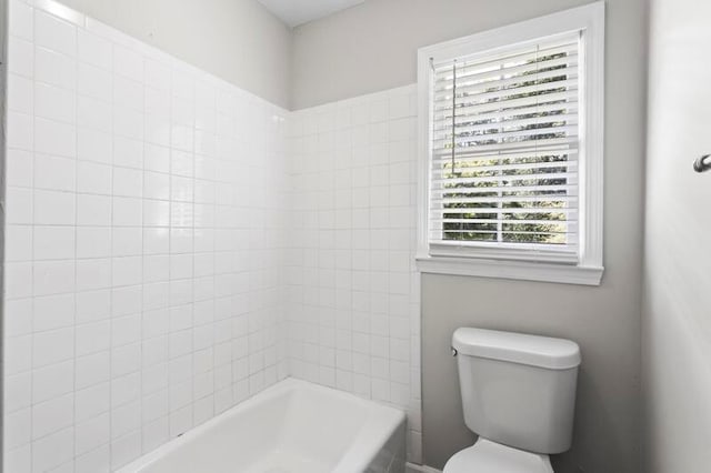 bathroom with tiled shower / bath combo and toilet