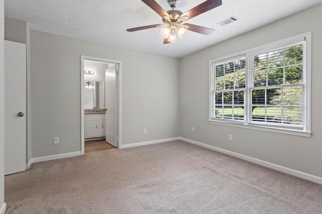 unfurnished bedroom featuring ensuite bathroom, ceiling fan, and light colored carpet