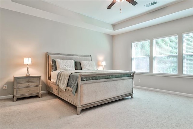 carpeted bedroom featuring ceiling fan and a tray ceiling