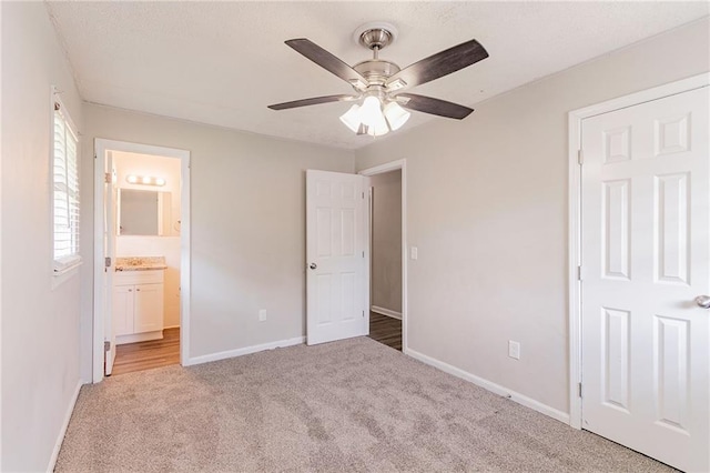 unfurnished bedroom featuring ceiling fan, light colored carpet, and ensuite bathroom