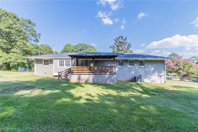 rear view of house featuring cooling unit and a lawn