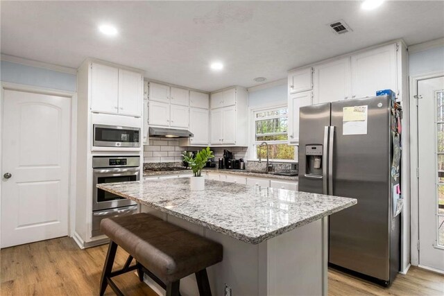 7275 Oswego Trl, Riverdale, GA 30296 - kitchen with stainless steel appliances, under cabinet range hood, white cabinets, and a warming drawer