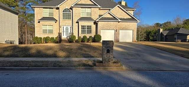 view of front facade featuring an attached garage, a chimney, and concrete driveway