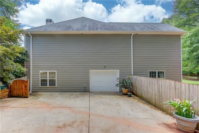 161 Southampton Cir, Hoschton, GA 30548 - view of side of home featuring concrete driveway, a chimney, an attached garage, and roof with shingles