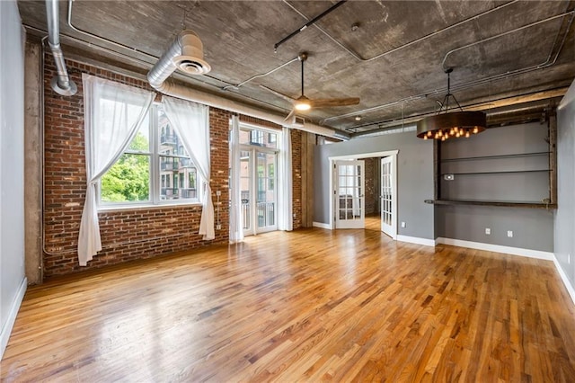 3235 Roswell Rd NE Unit 521, Atlanta, GA 30305 - unfurnished living room with wood finished floors, brick wall, baseboards, and french doors