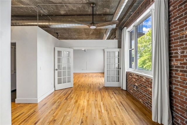 3235 Roswell Rd NE Unit 521, Atlanta, GA 30305 - empty room featuring french doors, hardwood / wood-style floors, baseboards, brick wall, and a ceiling fan