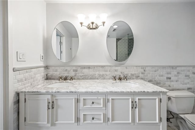 3235 Roswell Rd NE Unit 521, Atlanta, GA 30305 - full bathroom featuring tile walls, toilet, double vanity, and wainscoting