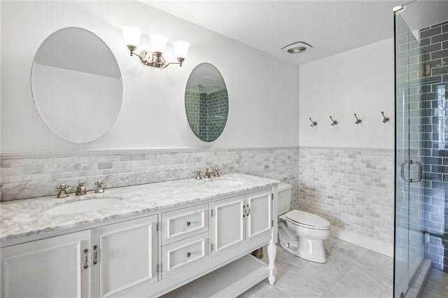 3235 Roswell Rd NE Unit 521, Atlanta, GA 30305 - bathroom featuring tile walls, toilet, double vanity, a stall shower, and a wainscoted wall